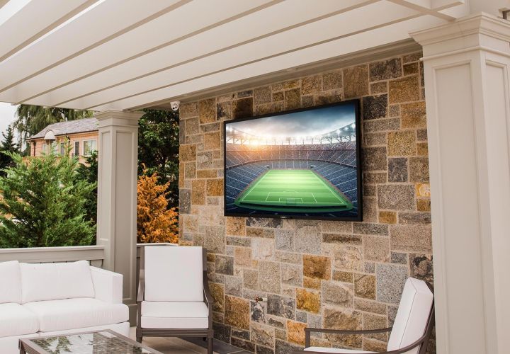 Outdoor patio with a wall mounted TV showing a soccer field