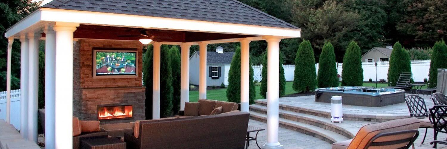 Outdoor pavilion with a TV over a fireplace and seating area