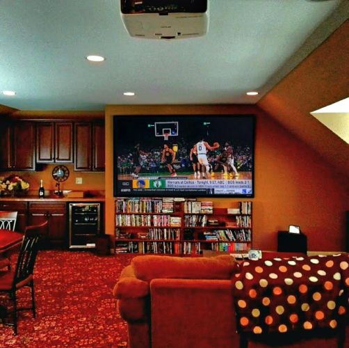 Media room with a large TV above shelves and a red carpet
