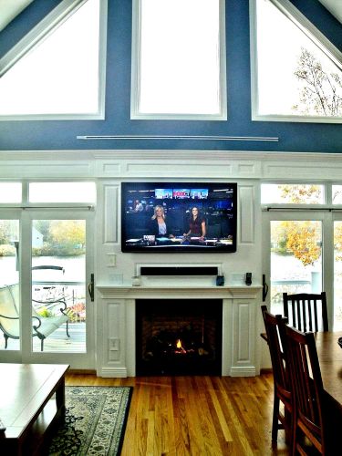 Living room with a wall mounted TV above a fireplace and large windows