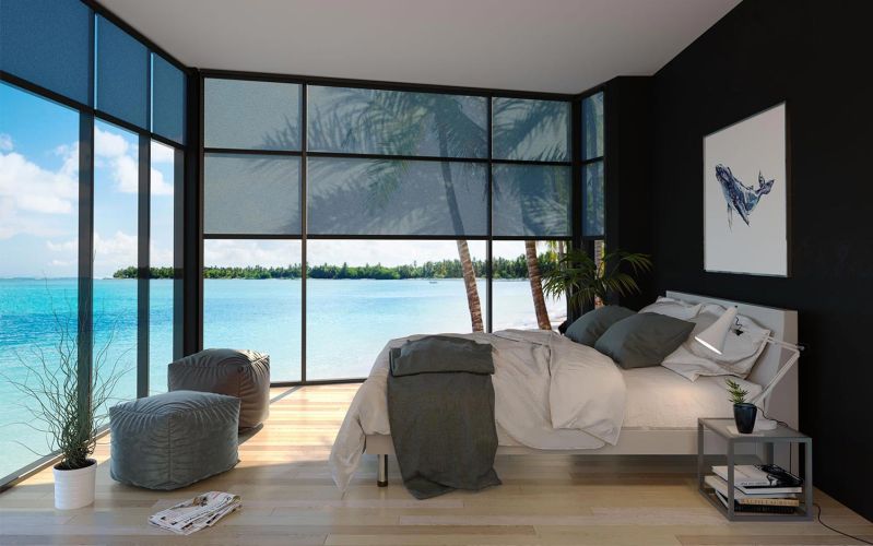 Bedroom with floor to ceiling windows overlooking turquoise water